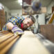 Portrait of experienced carpenter worker cutting wood plank on the machine in his woodworking workshop.